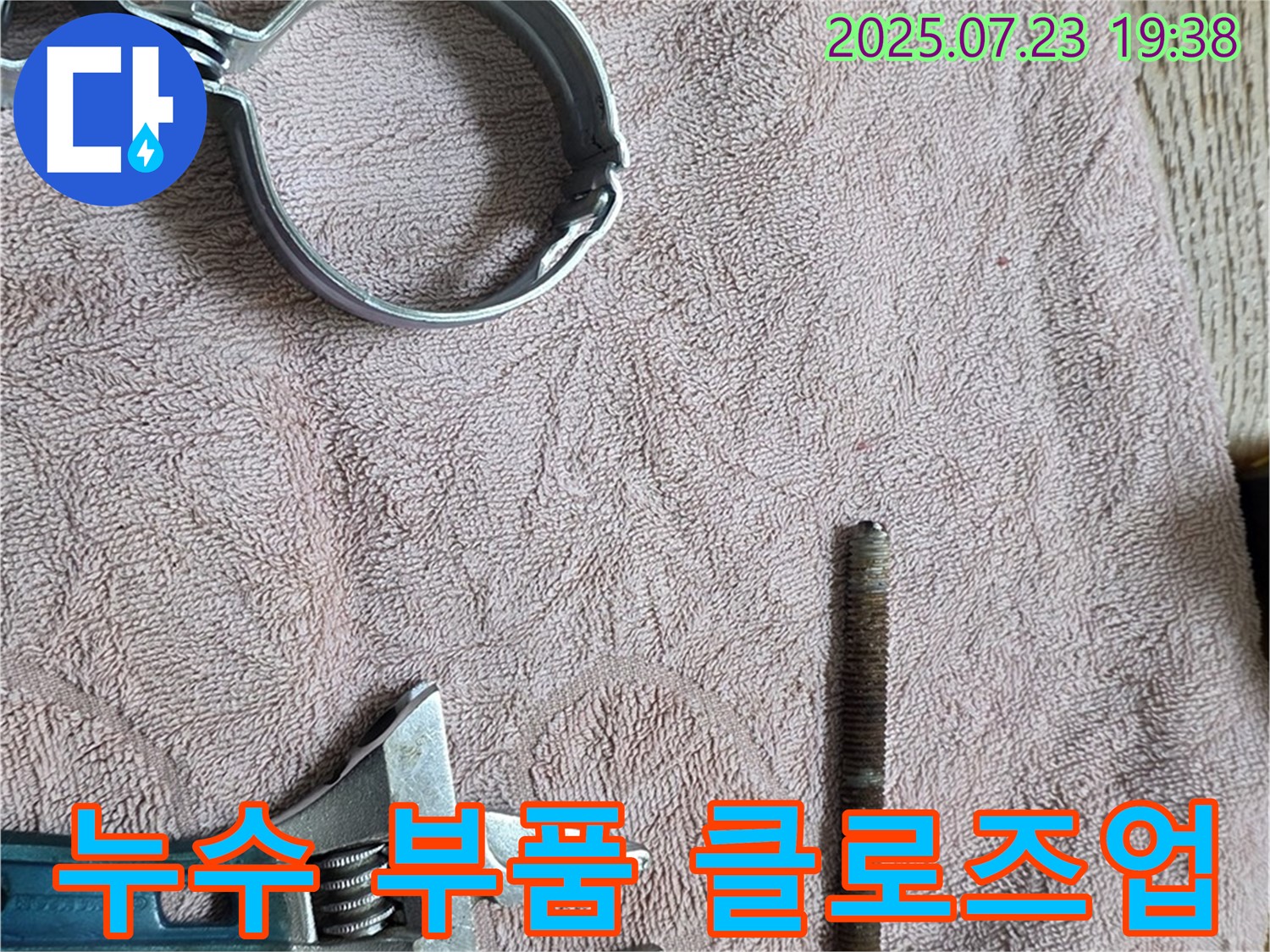 누수 공사에 사용될 부품을 가까이에서 촬영한 사진 - 클램프와 파이프 연결 부속이 정밀하게 놓여 있습니다.