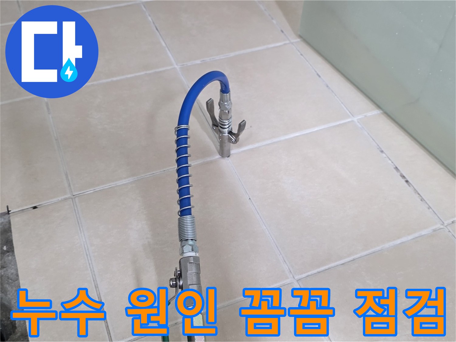 화장실 타일 바닥 위로 연결된 파란색 호스와 점검 도구