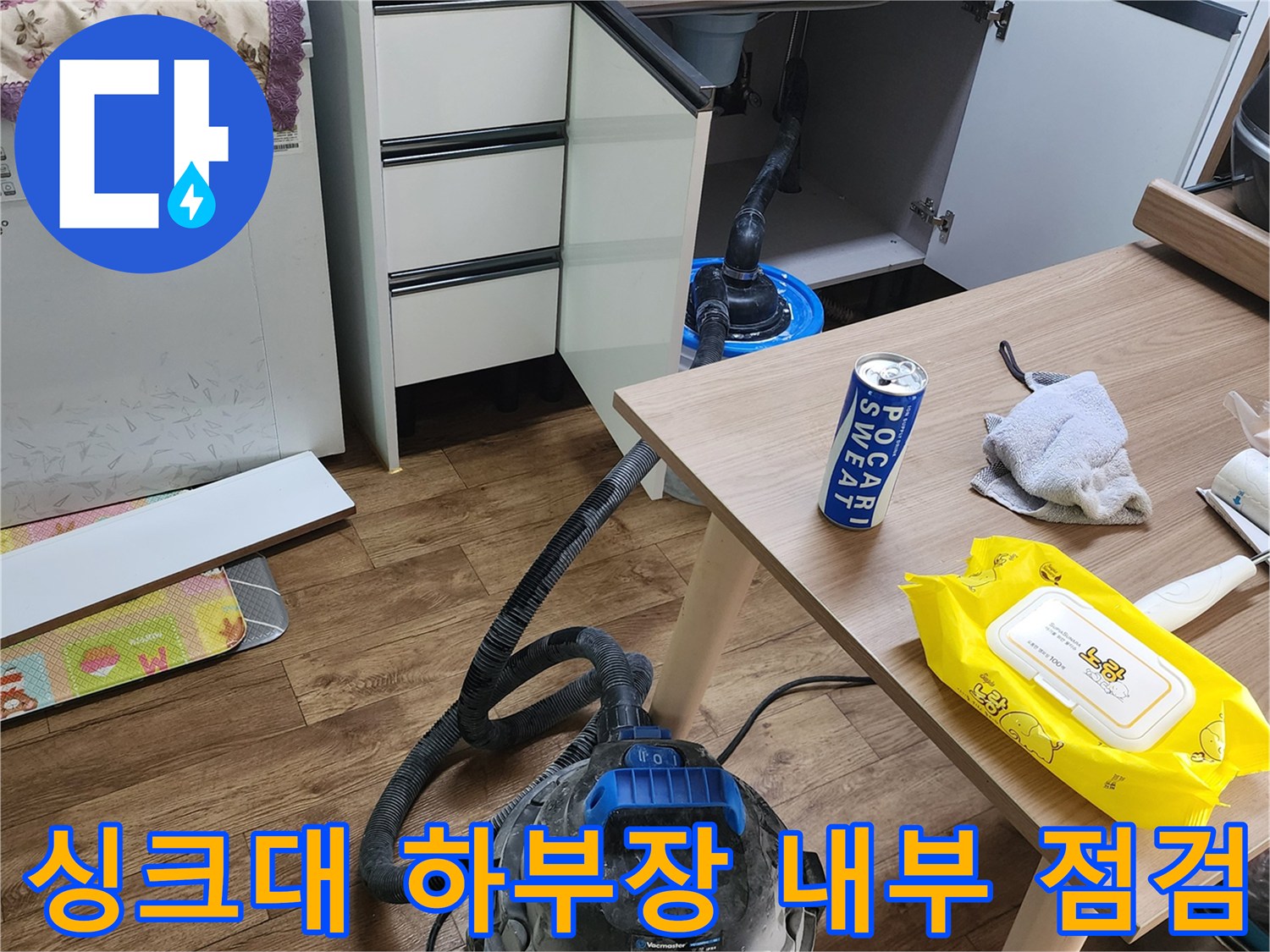 싱크대 밑부분의 누수 지점을 확인하기 위해 개방된 공간과 장비들