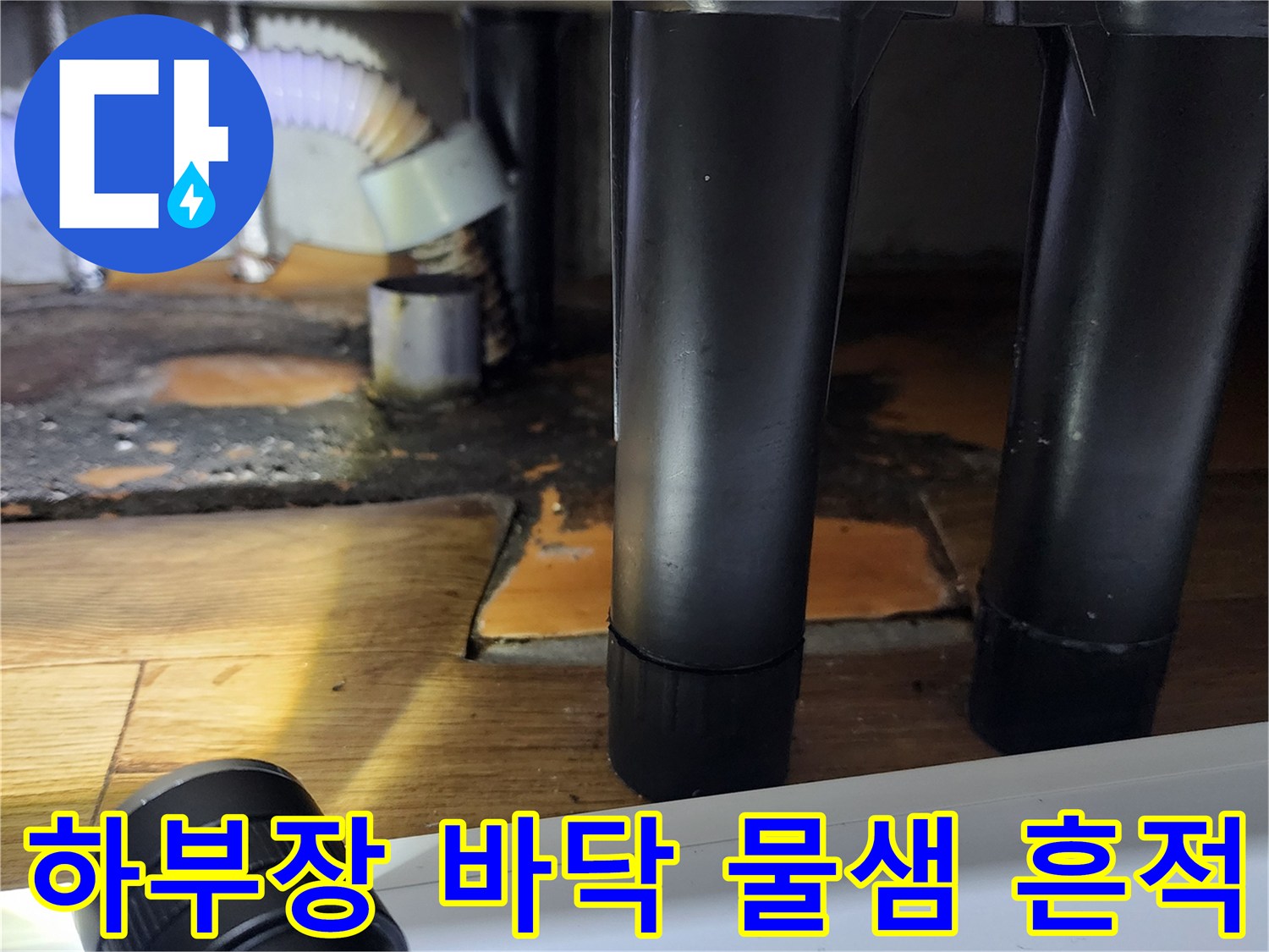 싱크대 아래쪽 배관 근처의 젖은 바닥과 오염된 마감재 부위