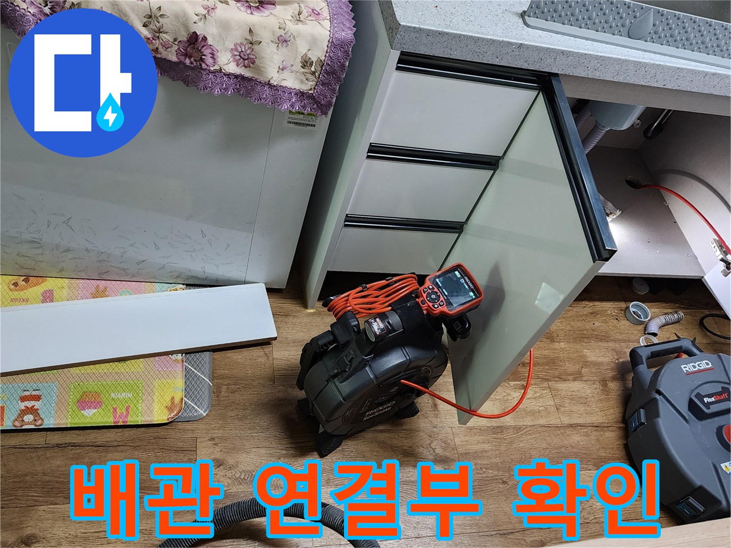 싱크대 하부장 내부의 수전과 배관 연결 상태를 점검 중입니다