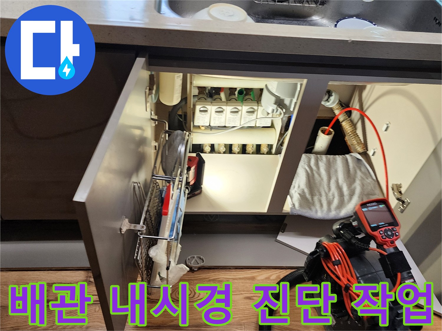 전문 내시경 카메라를 사용하여 싱크대 하부 배수관 내부를 조사하는 장면