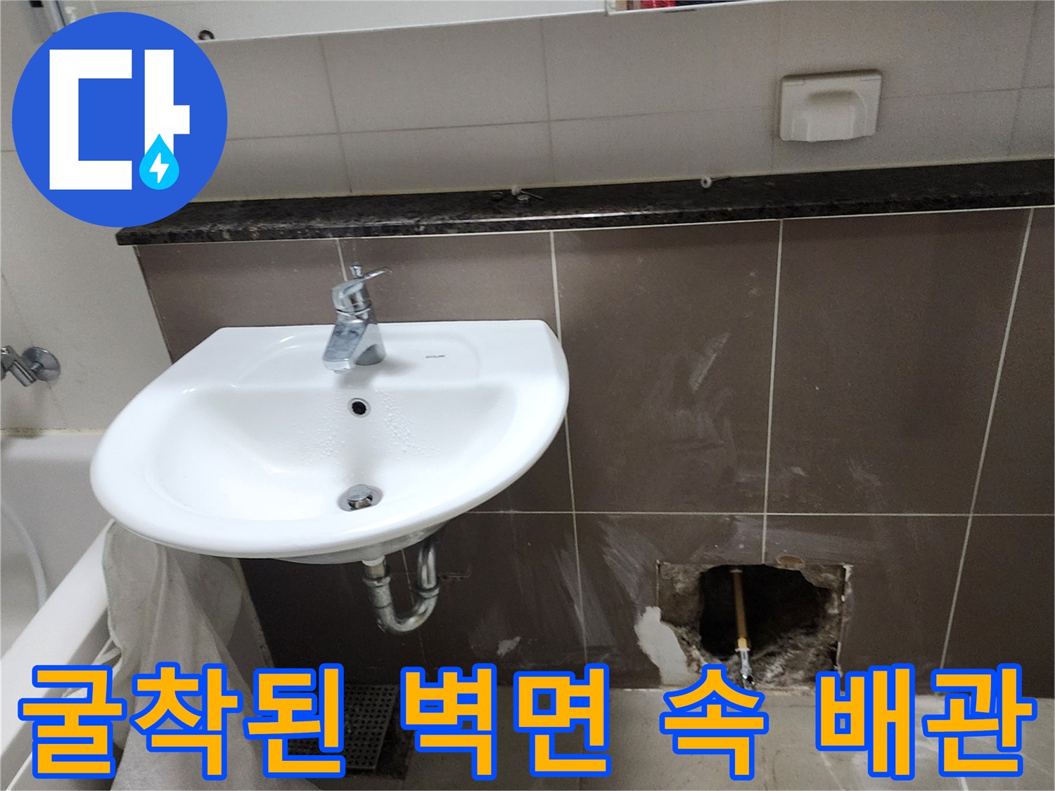 세면대 아래 타일을 제거하여 노출된 수도 연결 배관