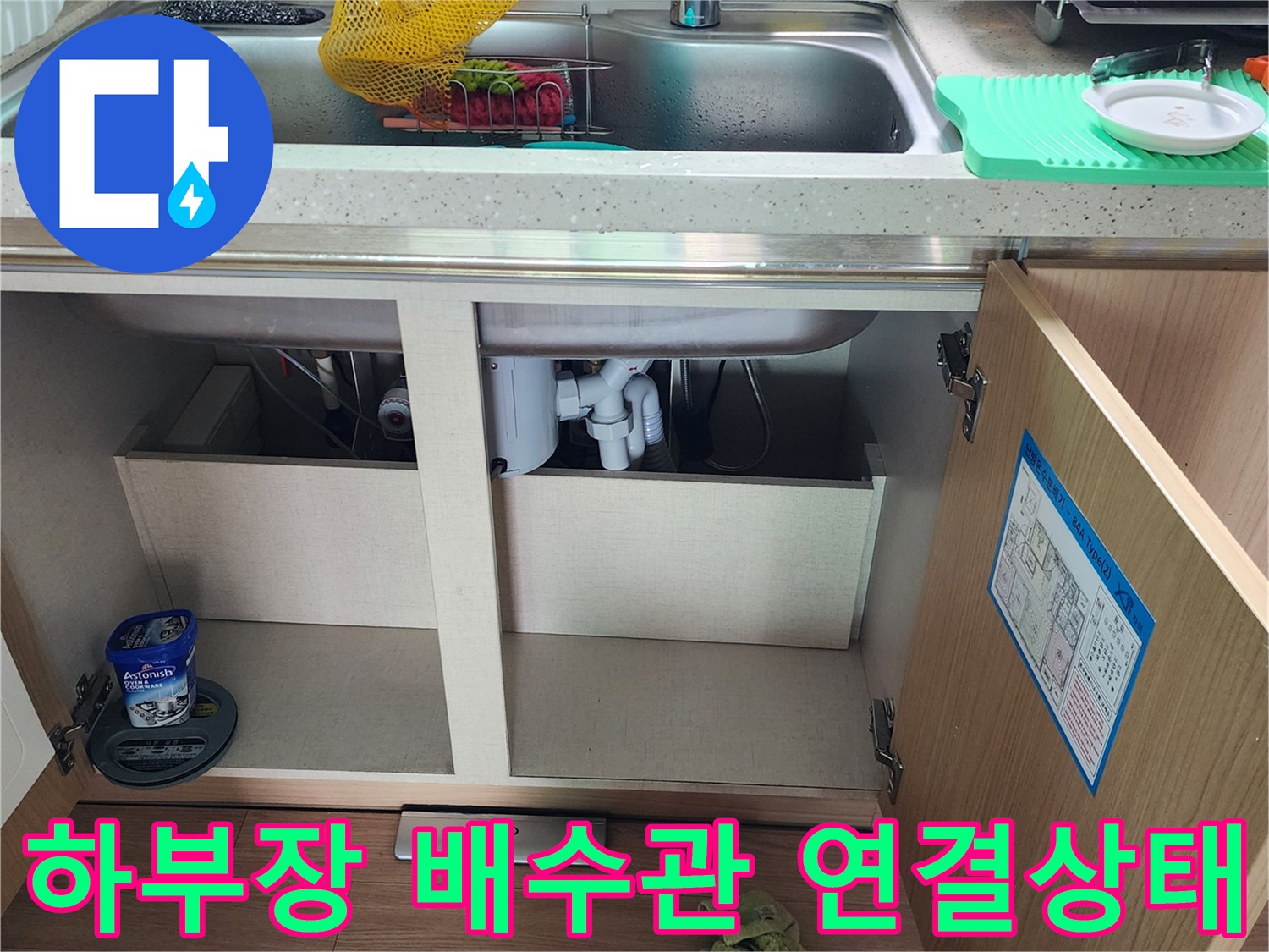 싱크대 하부장 내부의 복잡한 배수관 구조와 연결 상태를 보여줍니다.