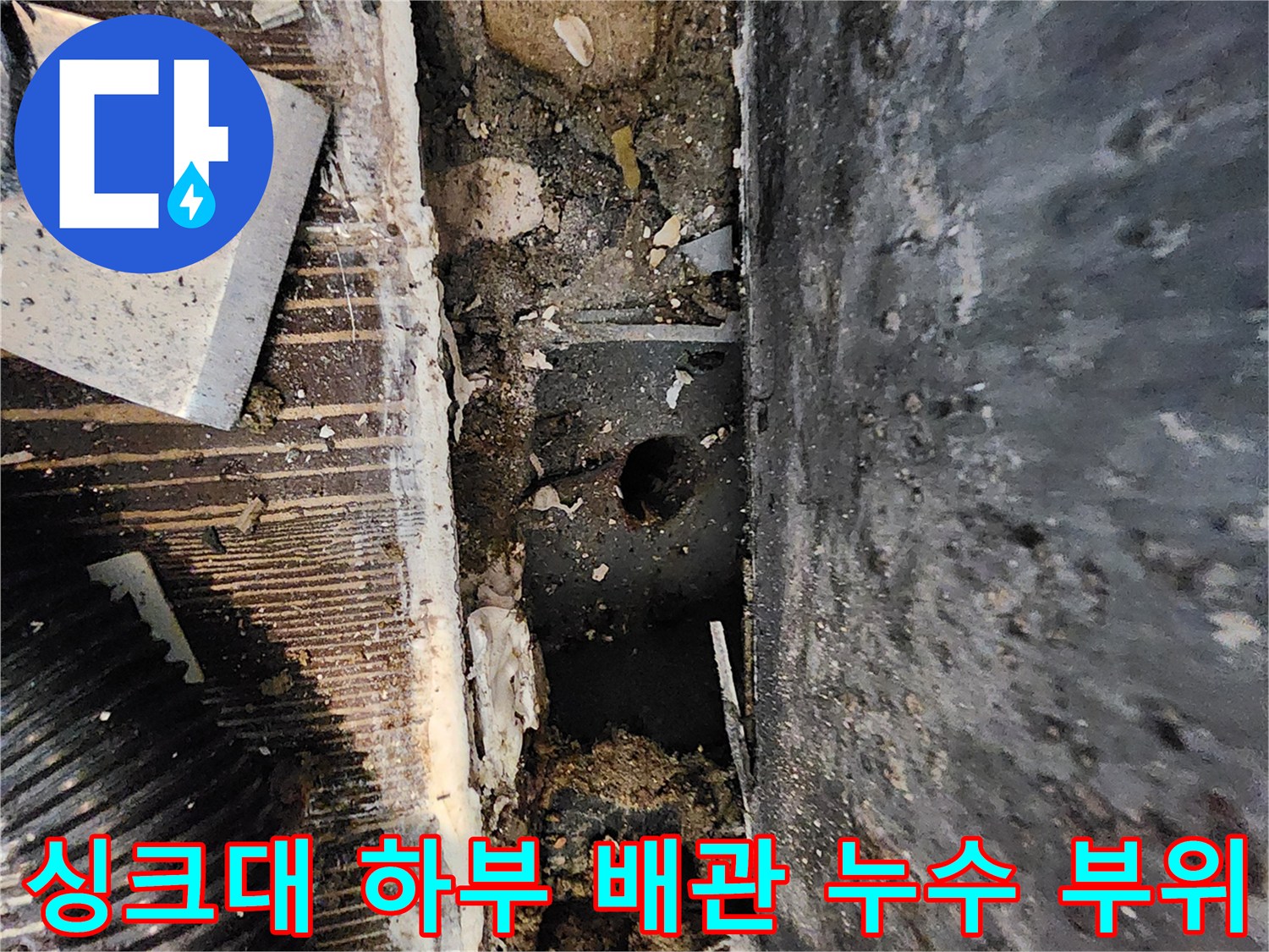 양주시 삼숭동 현장의 싱크대 걸레받이를 제거한 후 드러난 젖은 바닥과 배관 주변의 상태를 보여주는 사진입니다.