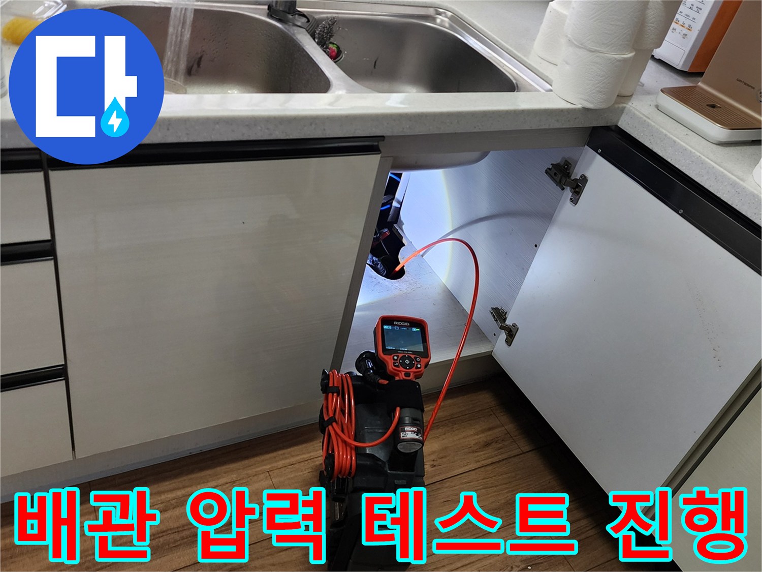 싱크대 하부 배관 연결 부위에 공압 장비를 연결하여 누수 여부를 진단하는 모습