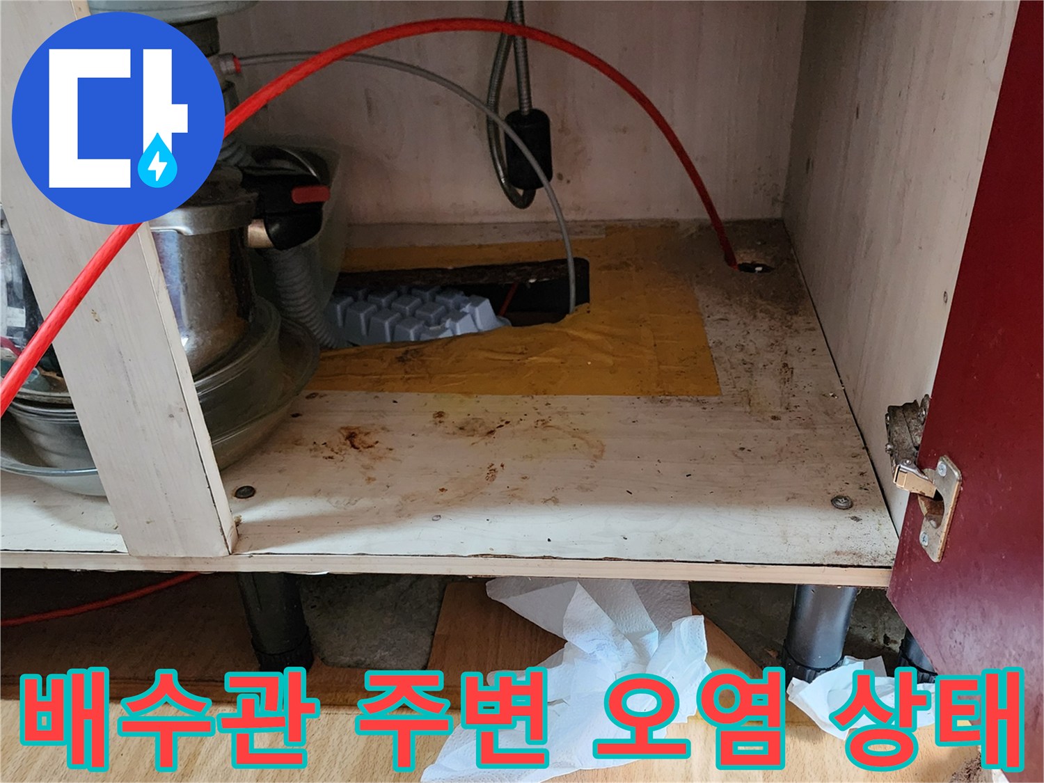 주방 싱크대 밑-배관 연결 부위의 습기와 변색된 목재 상태를 촬영한 이미지