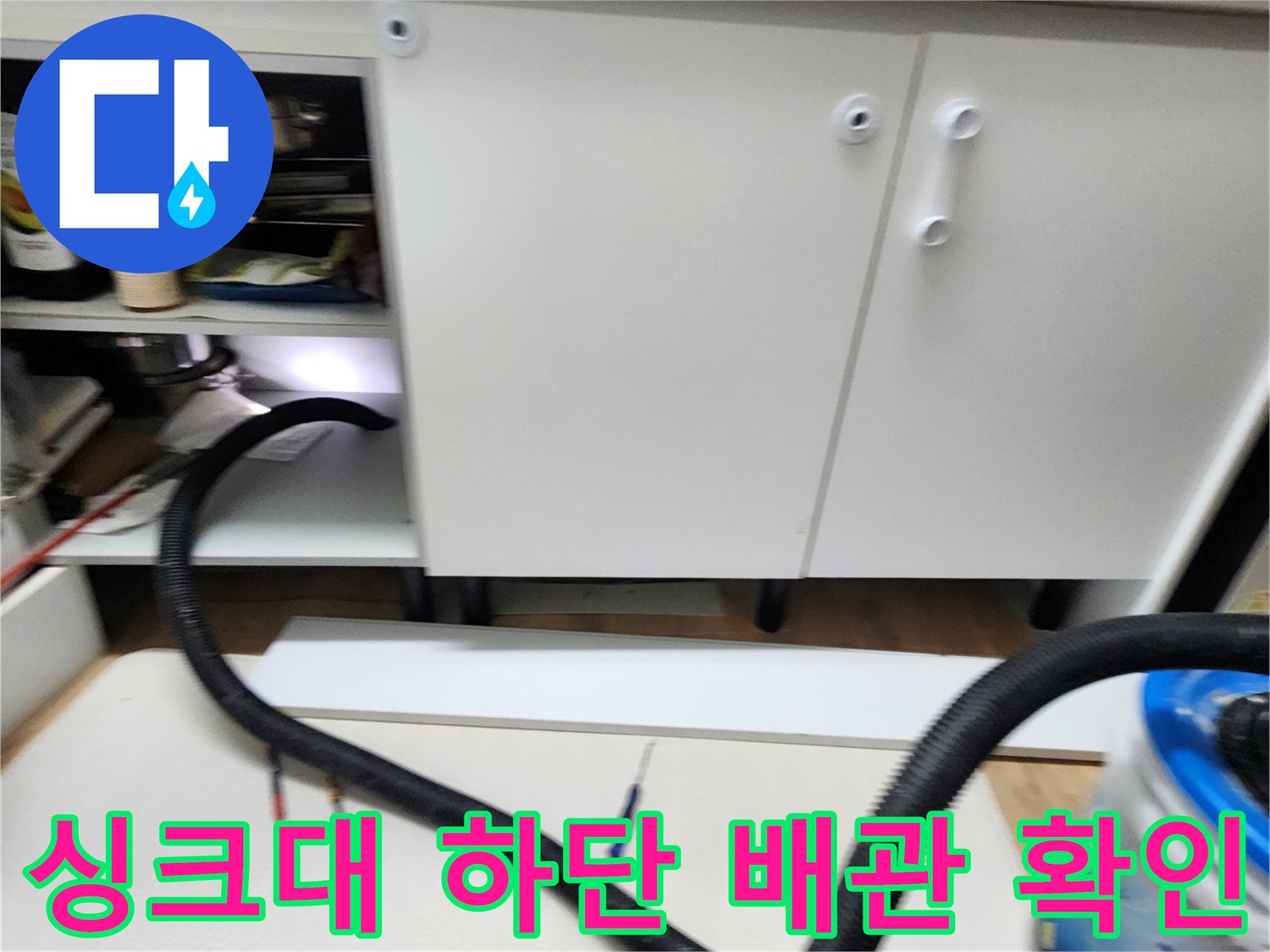 싱크대 하부장 내부의 배관 연결 부위를 살펴보는 사진입니다.