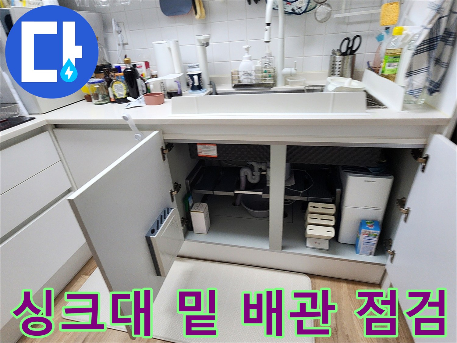 열려 있는 싱크대 하부장 내부의 배관 및 매립함 구조