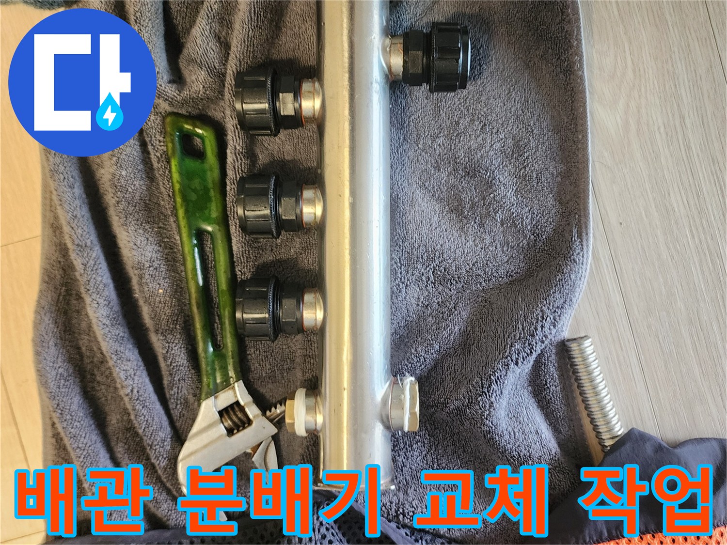 작업용 몽키스패너와 새 배관 분배기가 놓여 있는 모습