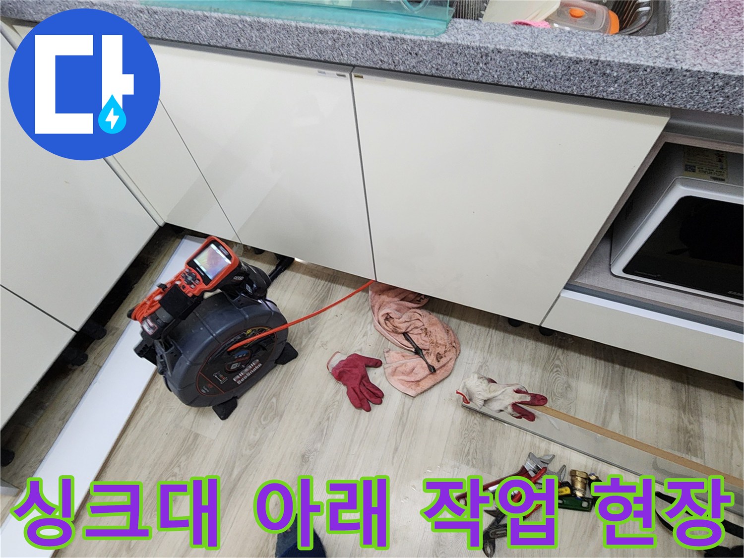 싱크대 하부 공간에 놓인 디지털 압력계와 각종 수리용 공구들입니다.