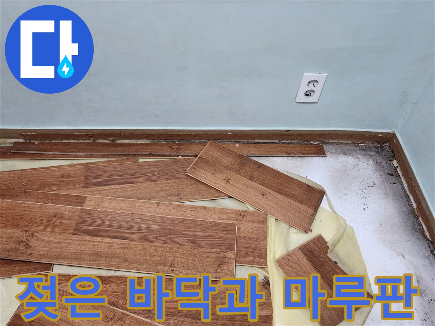 공사 현장 기록-벽면 하단부의 습기 오염과 흩어져 있는 마루 자재