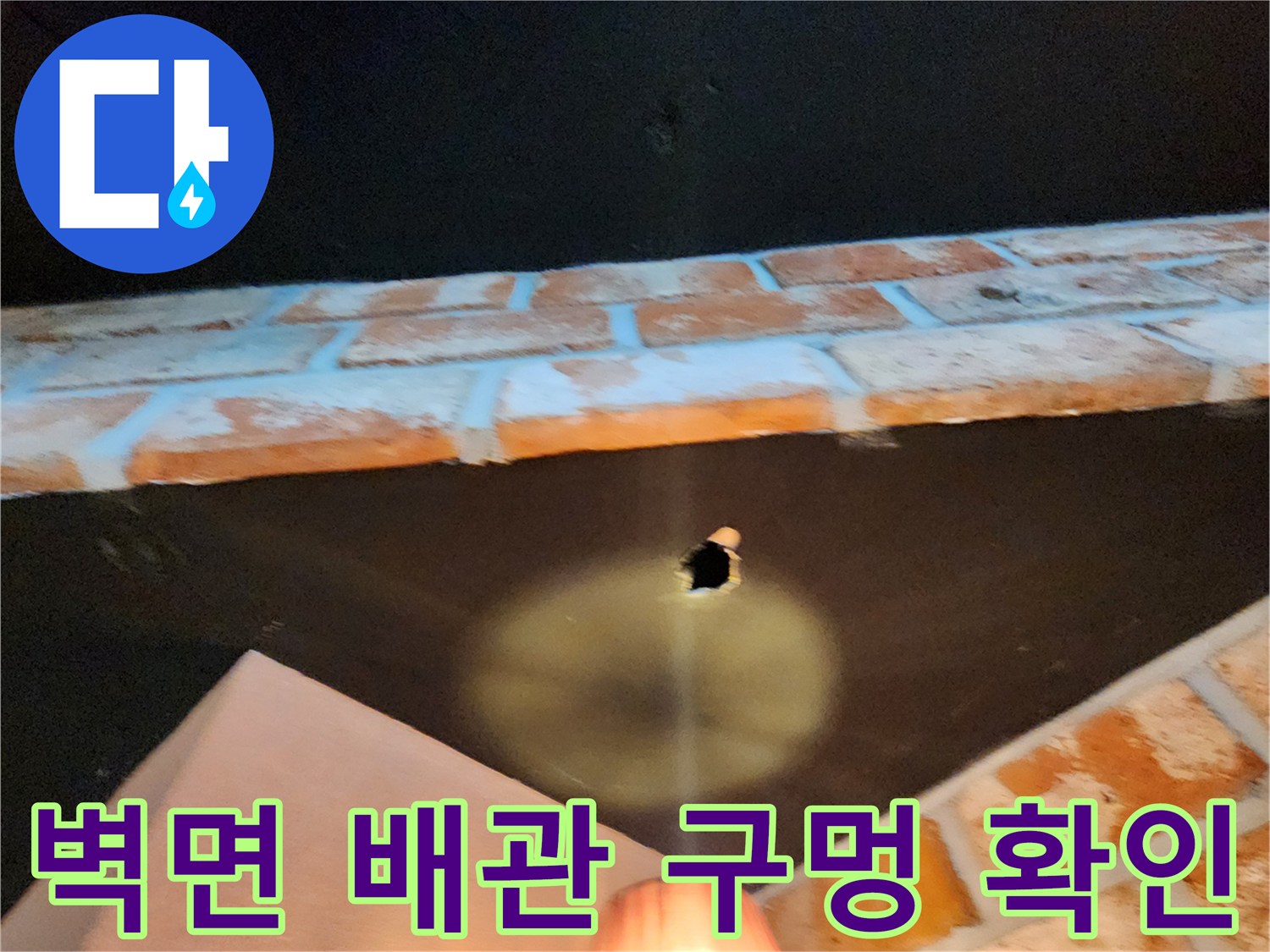벽돌 벽체 사이로 노출된 배관 연결 부위의 구멍 상태를 보여줍니다.