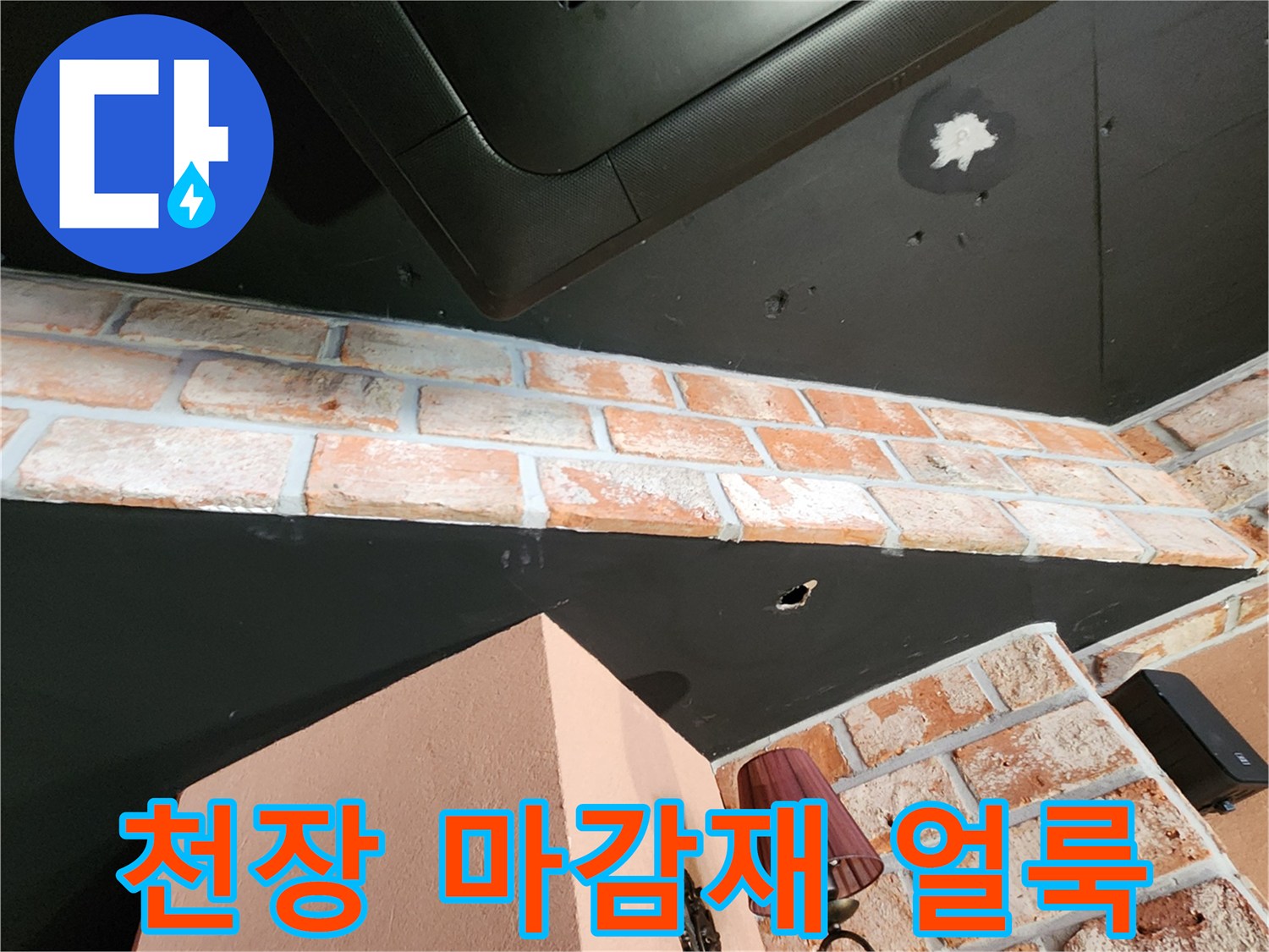 검은색 천장 패널에 나타난 하얀 누수 흔적과 벽돌 벽면