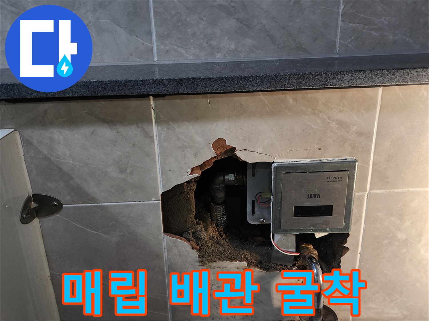 타일을 제거하여 드러난 소변기 급수 배관과 자동 밸브 유닛
