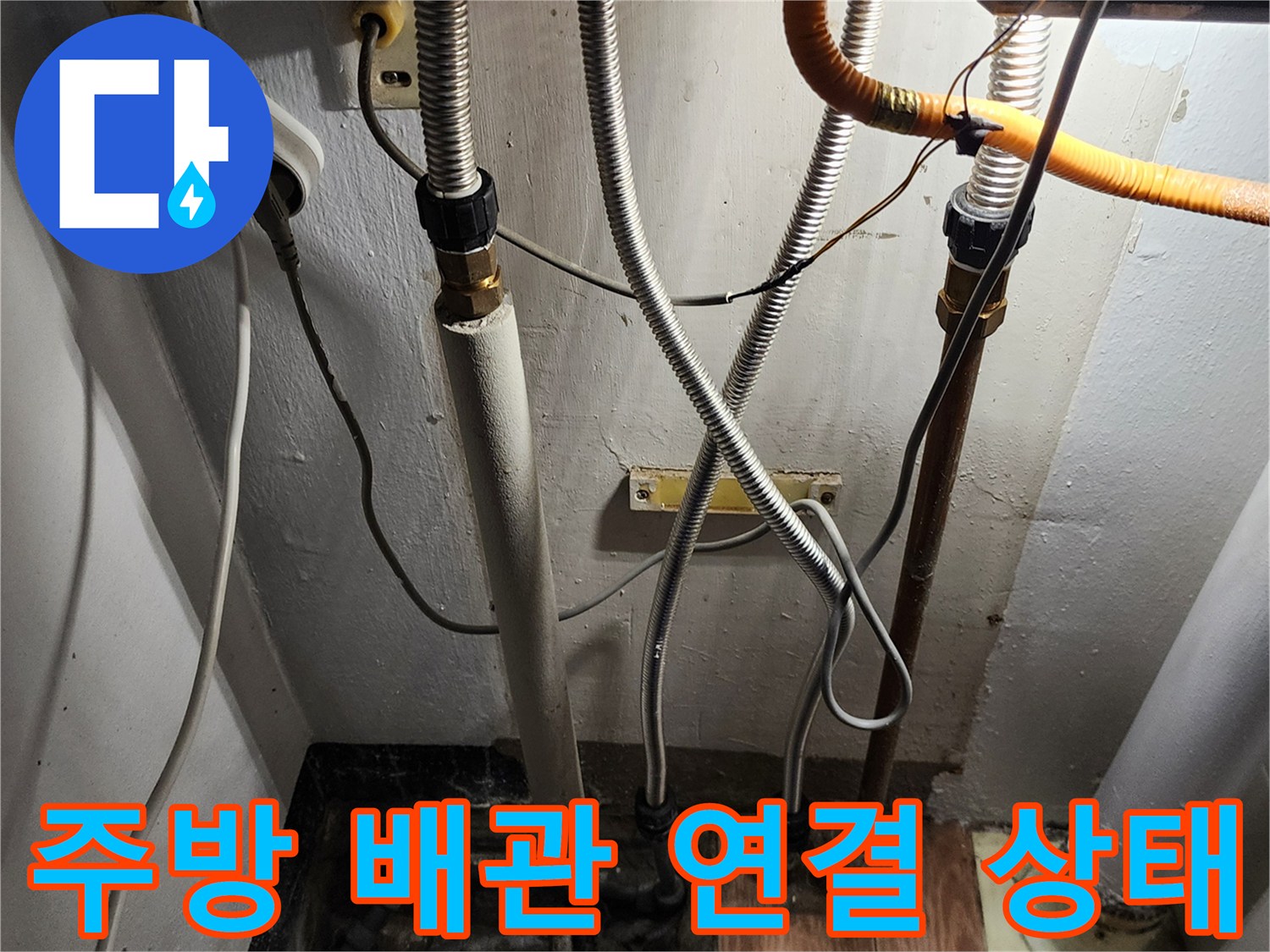 주방 싱크대 하부의 복잡한 배관 및 연결 부위 모습
