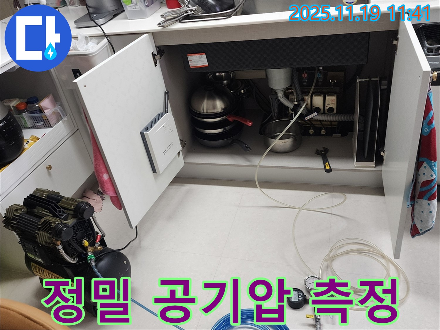 포천 내촌 누수 현장 - 싱크대 하부에서 정밀 공기압 측정 장비를 사용하여 압력을 측정하는 모습입니다.