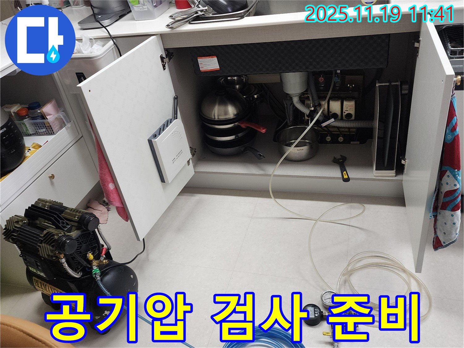 포천시 내촌면 마명리 누수 현장 - 싱크대 하부에서 공기압 검사를 준비하는 모습입니다. 꼼꼼하게 장비를 살펴보고 있습니다.