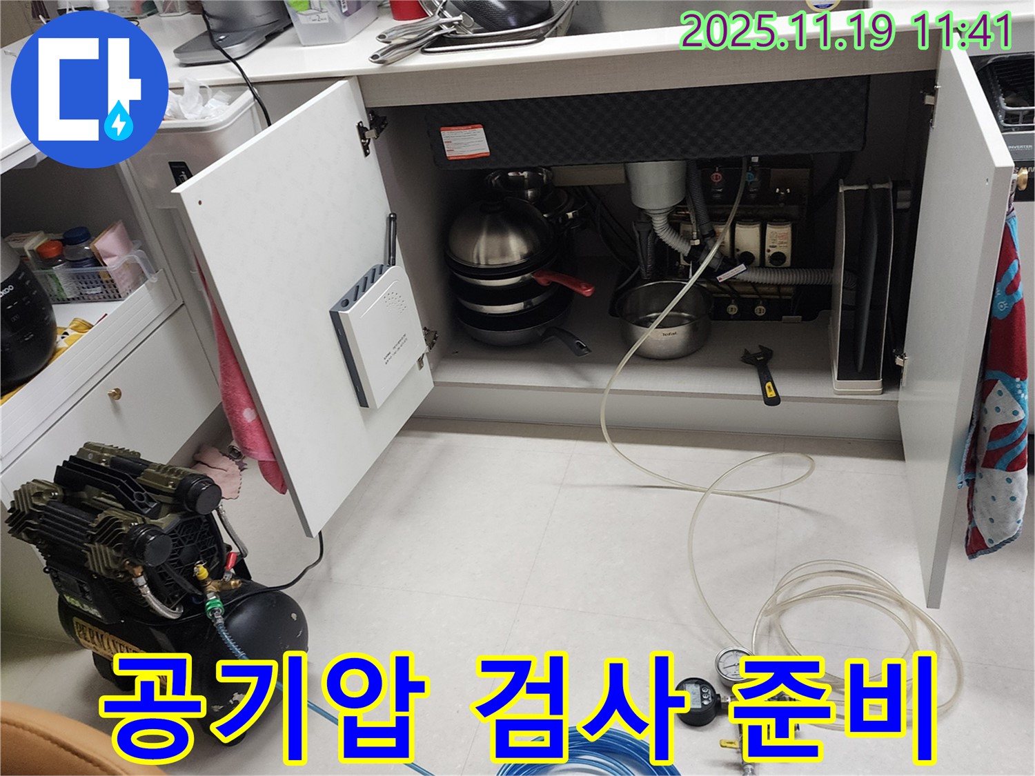 포천시 내촌면 마명리 누수 현장 - 싱크대 하부에서 공기압 검사를 준비하는 모습입니다. 꼼꼼하게 장비를 살펴보고 있습니다.