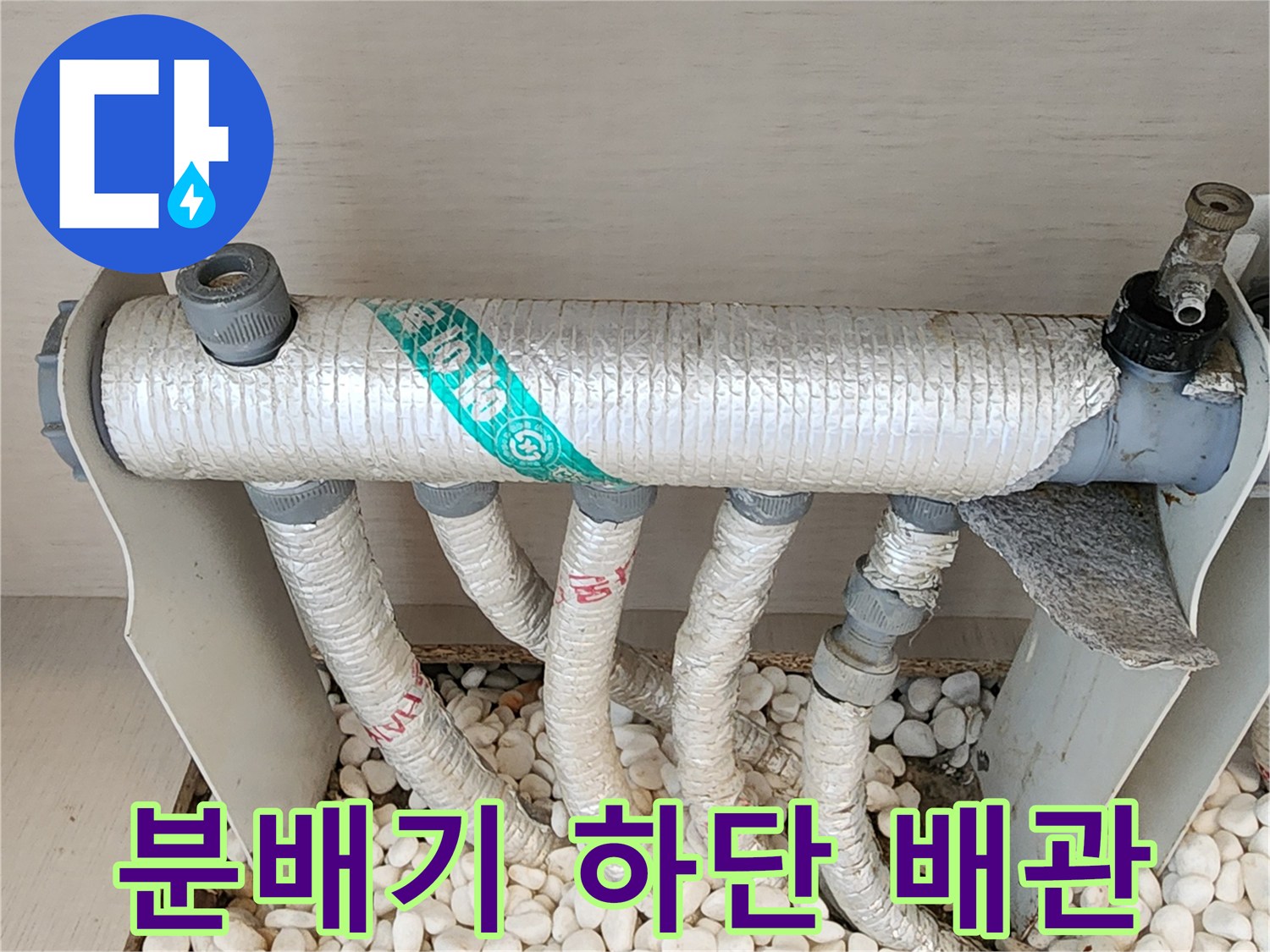 하얀 자갈 위에 놓인-보온재로 감싸진 분배기 배관