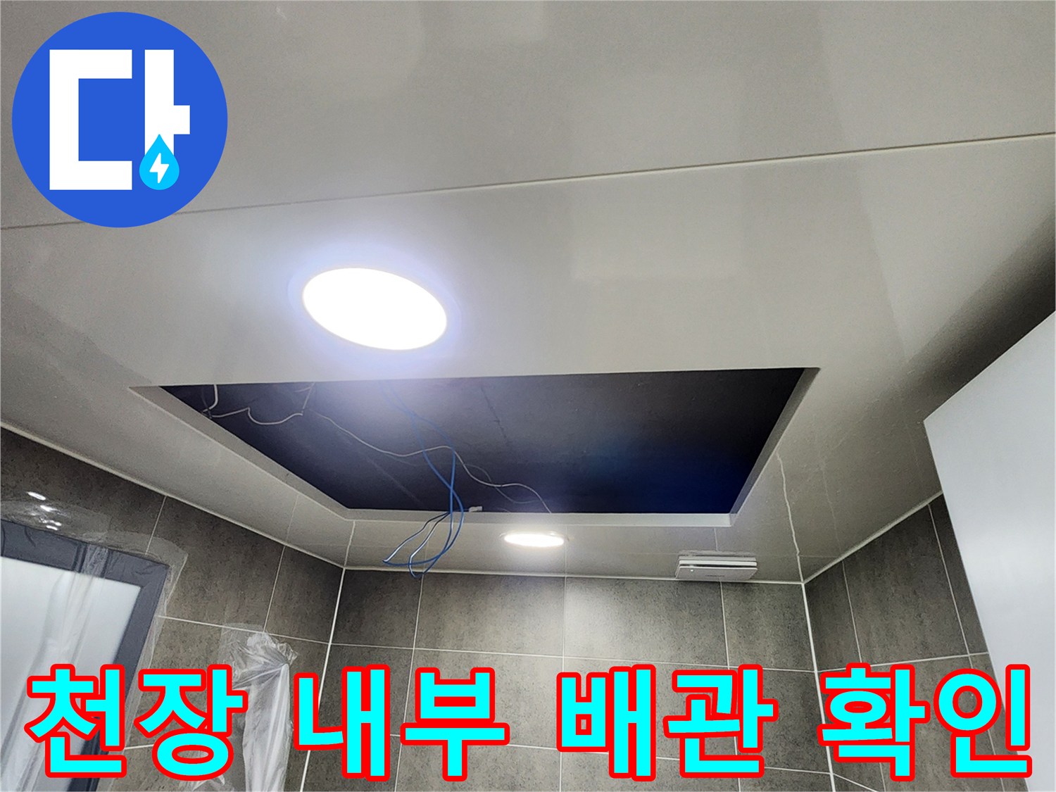 어두운 천장 점검구 안쪽의 배관 구조와 상태를 촬영한 사진입니다.