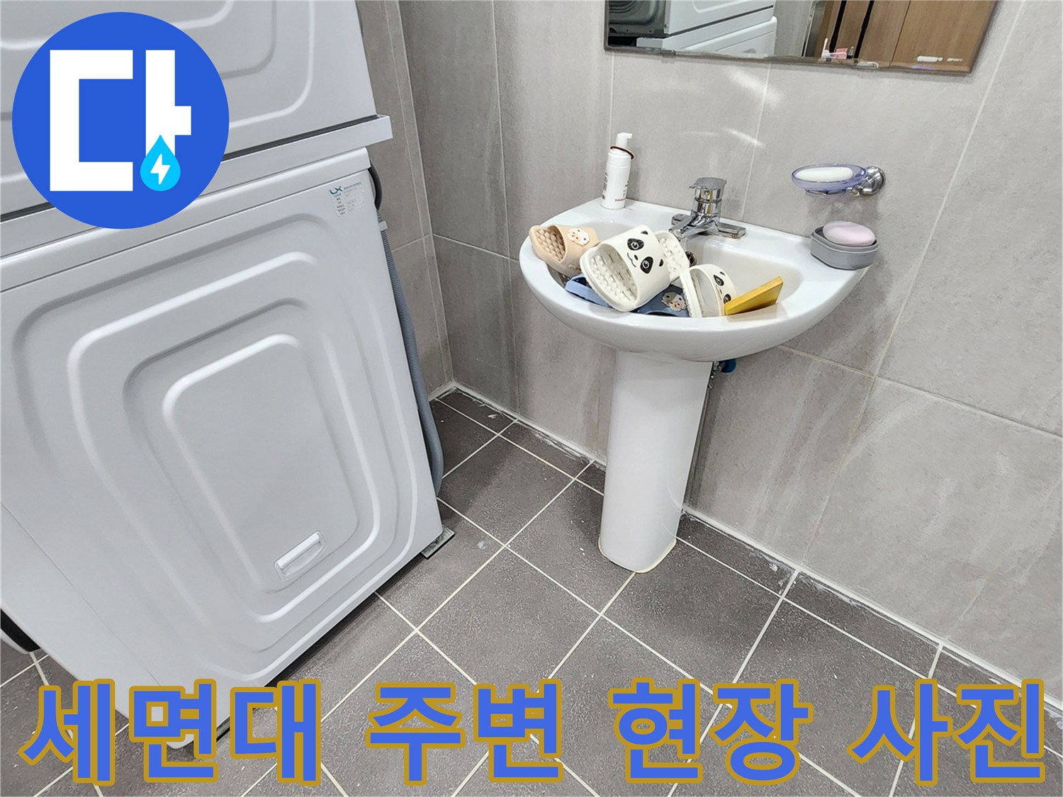 세면대와 세탁기 옆 공간의 타일 바닥 상태를 촬영한 이미지