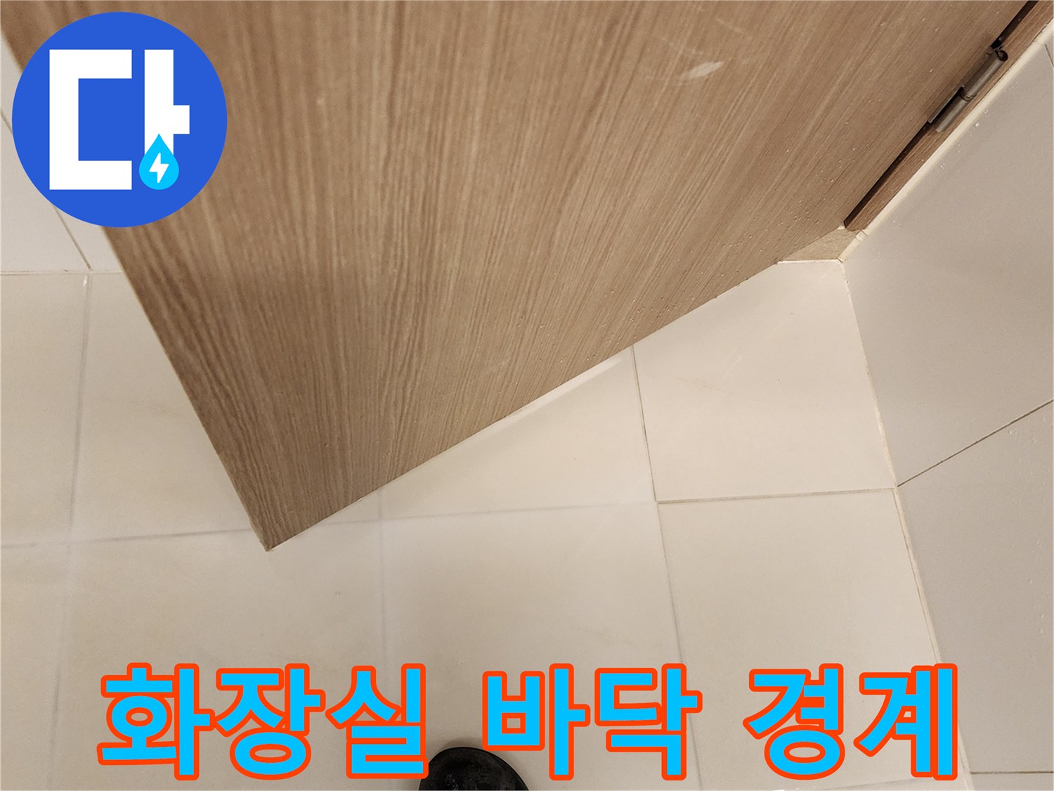 욕실 문 하단-밝은 타일과 나무 문의 접촉 부위 촬영