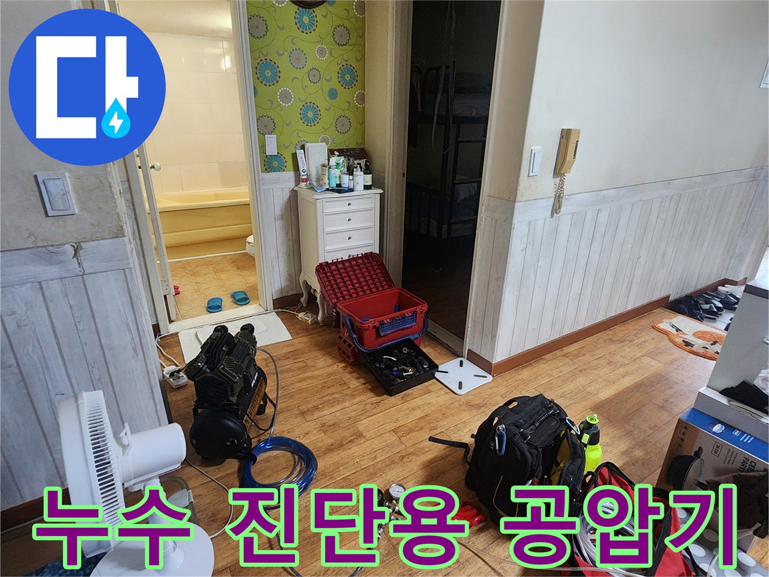 욕실 입구 바닥에 세팅된 배관 압력 점검용 전문 장비와 호스