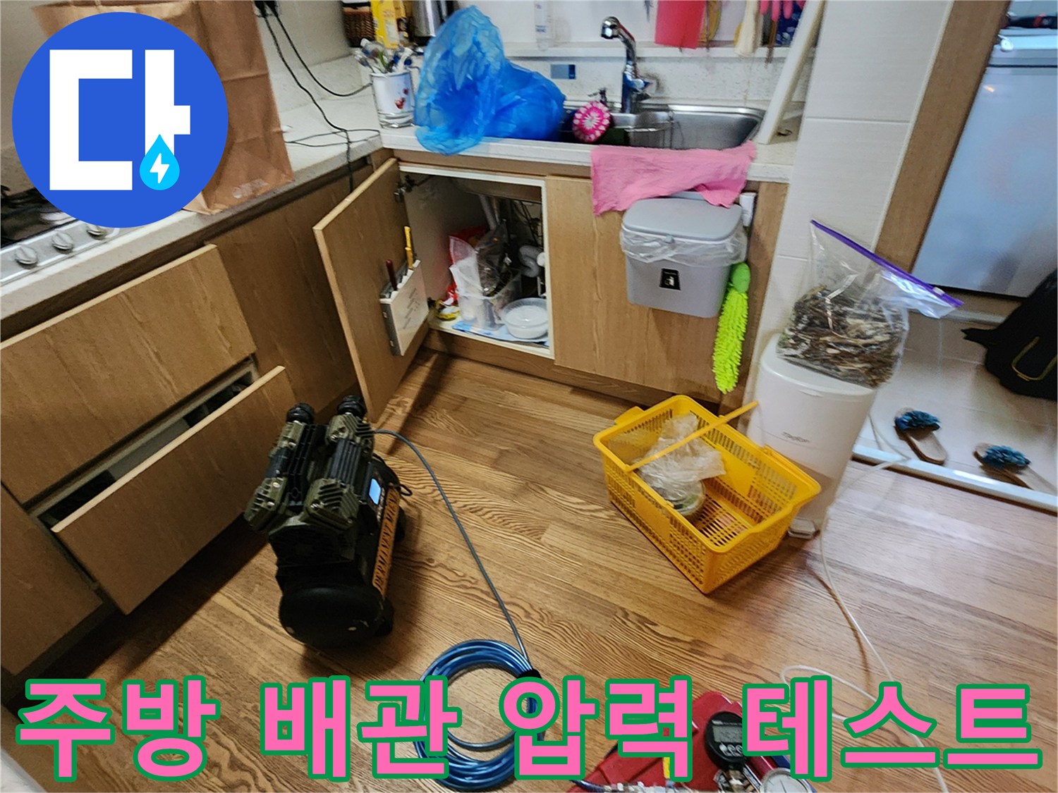 주방 싱크대 아래에 설치된 배관 압력 측정 장비와 공기압 테스트 현장