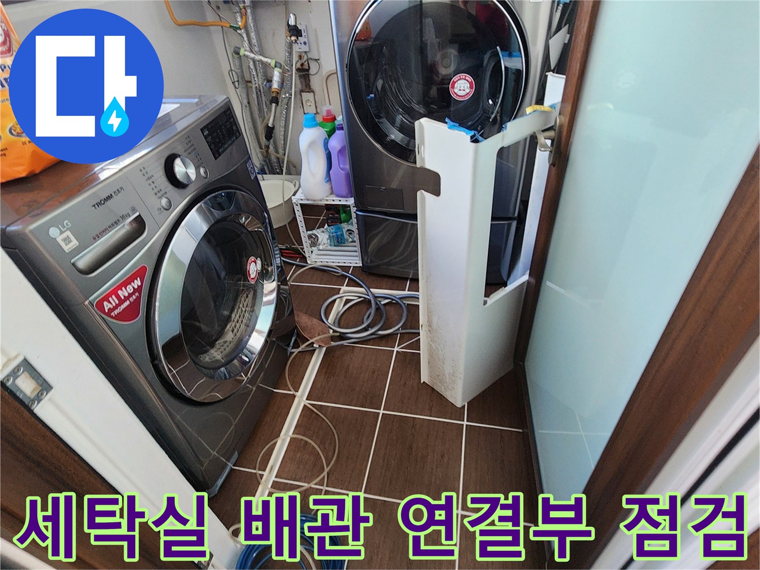 세탁기와 건조기 사이 공간의 배관과 호스들을 점검하는 모습