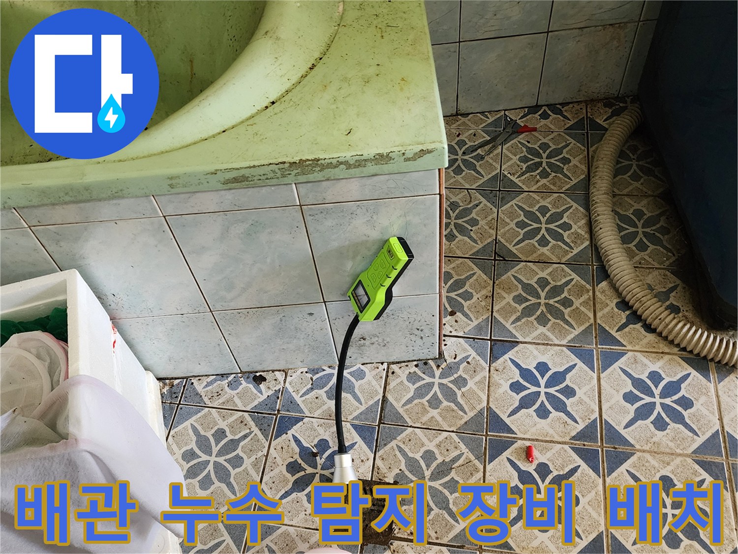 욕실 바닥 타일 위에 놓인 가스 탐지기와 연결된 검사 호스