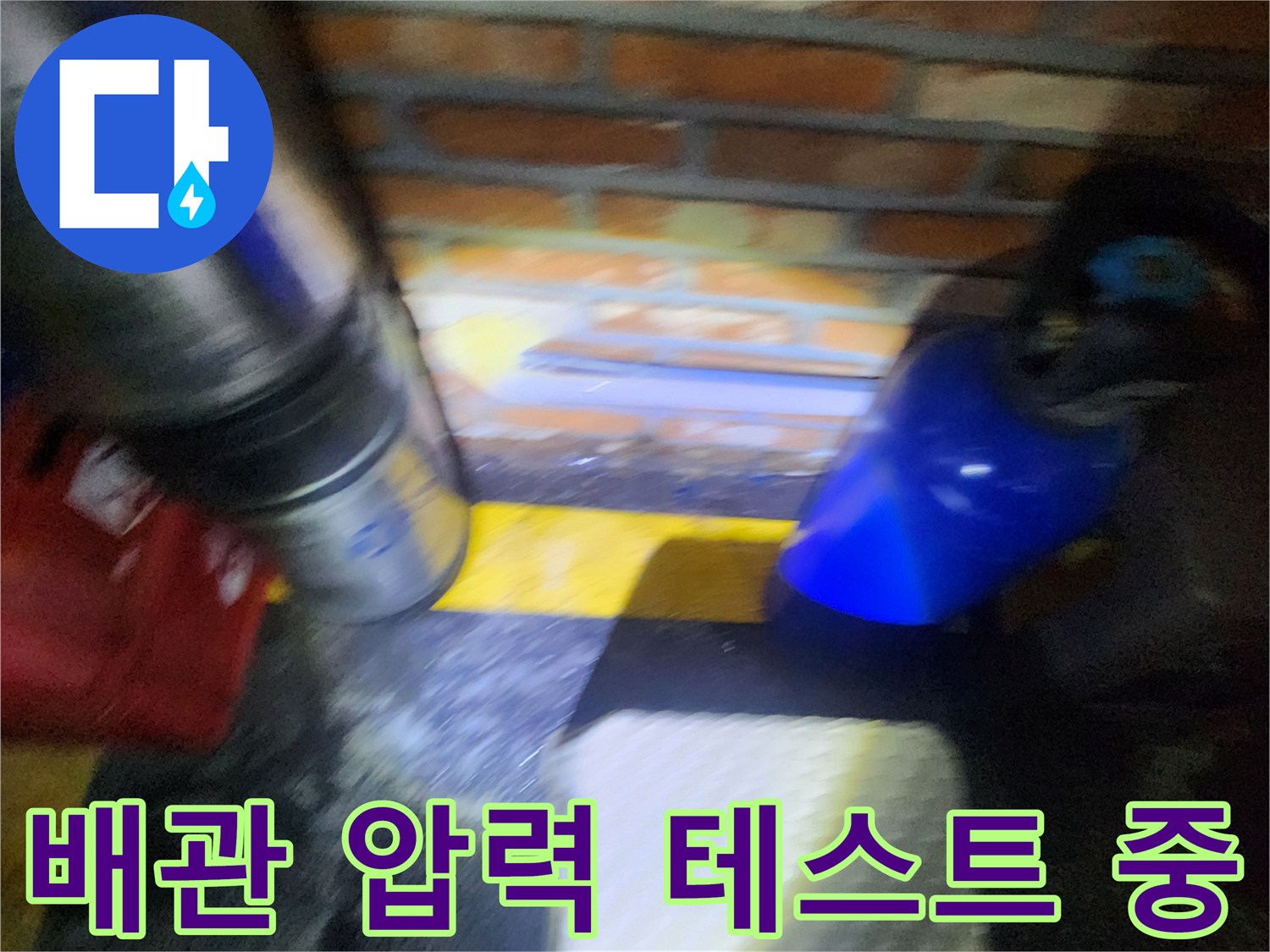 벽돌 벽면 아래 배치된 배관과 공압 측정 장비의 모습