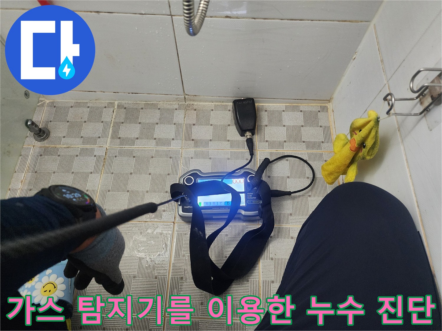화장실 바닥 타일 위에서 가스 탐지기를 작동시켜 배관의 이상 유무를 검사합니다.