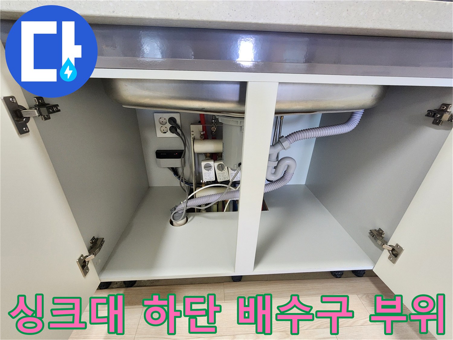 주방 싱크대 밑에 보이는 배수 호스와 급수 밸브 연결부 이미지