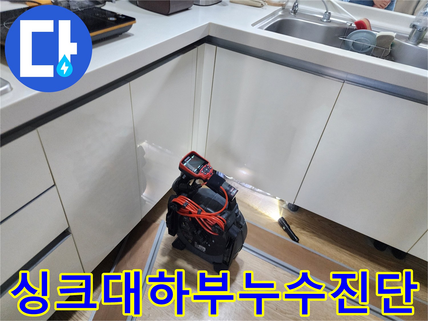 싱크대 아래쪽 배관의 결함을 찾기 위해 사용 중인 내시경 카메라와 장비