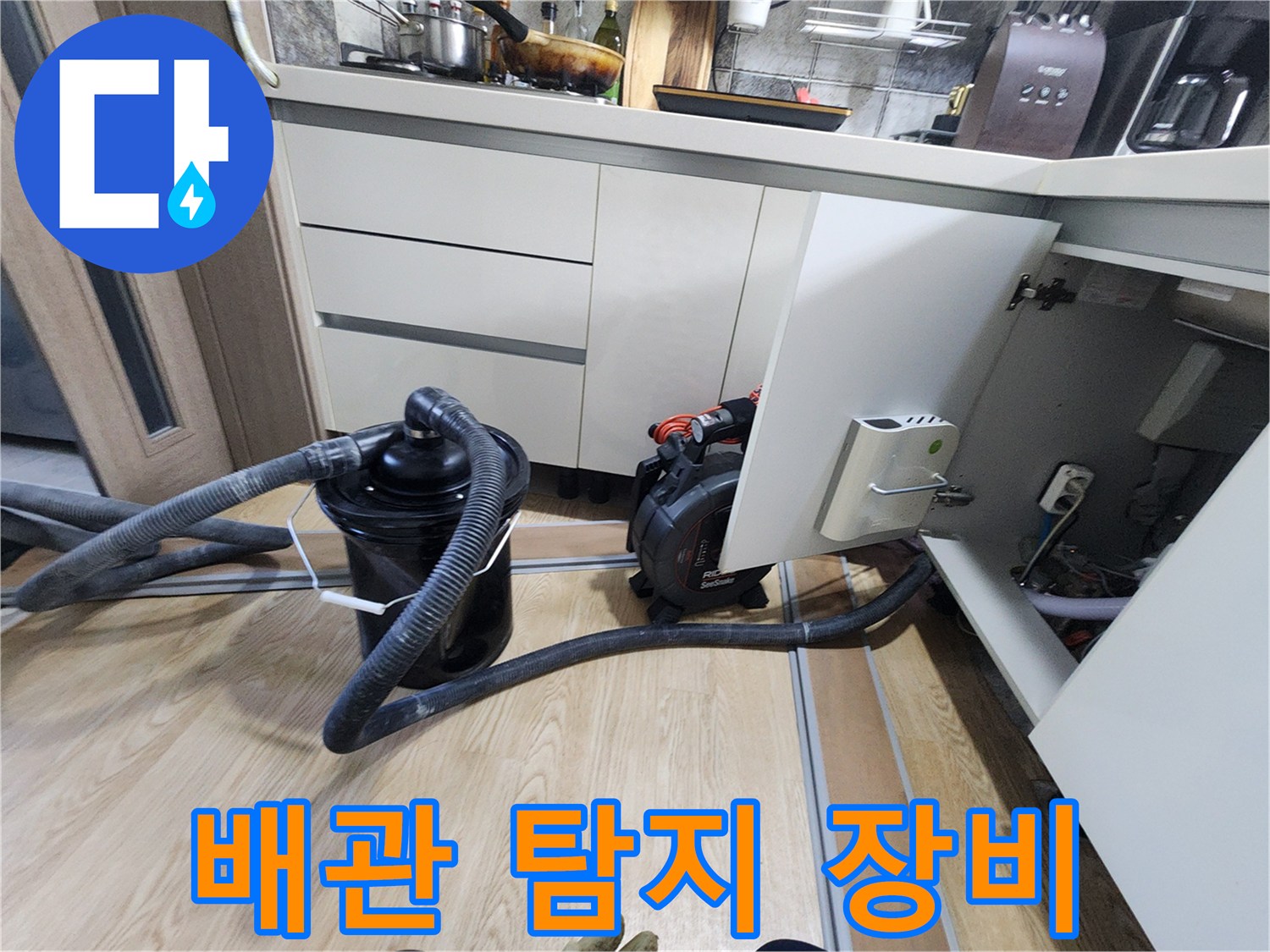 싱크대 하부 공간에 설치된 배관 점검용 진공 흡입기와 호스입니다.