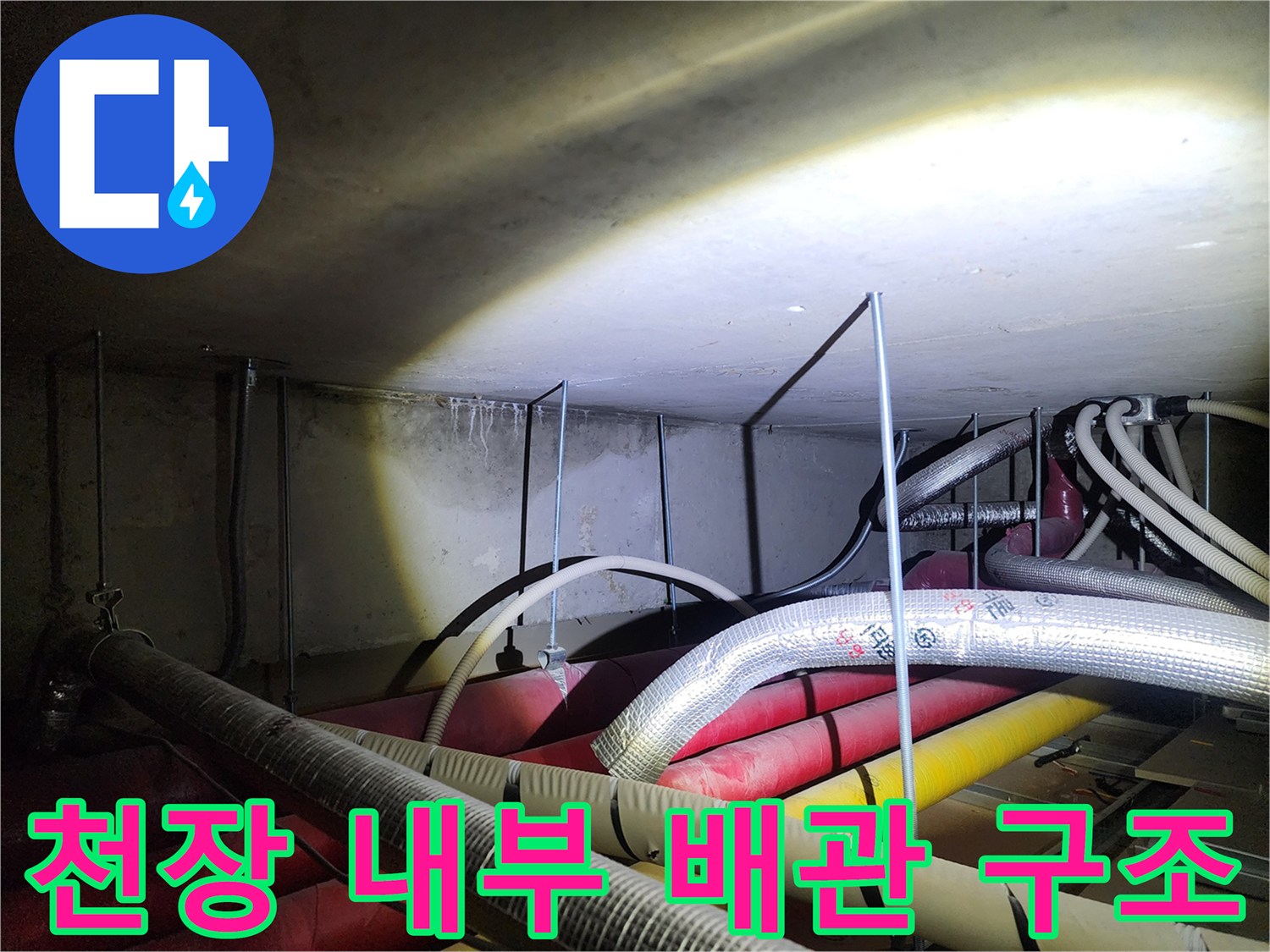 여러 갈래의 배관이 얽혀 있는 천장 내부 공간 사진입니다.