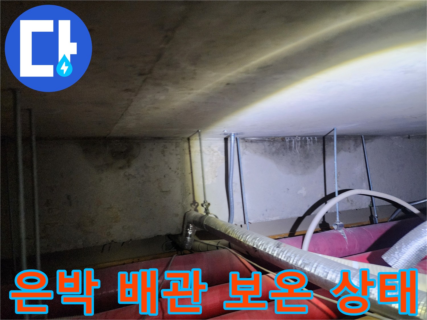 은박 재질의 보온재로 감싸진 배관이 지나가는 천장 내부 모습입니다.