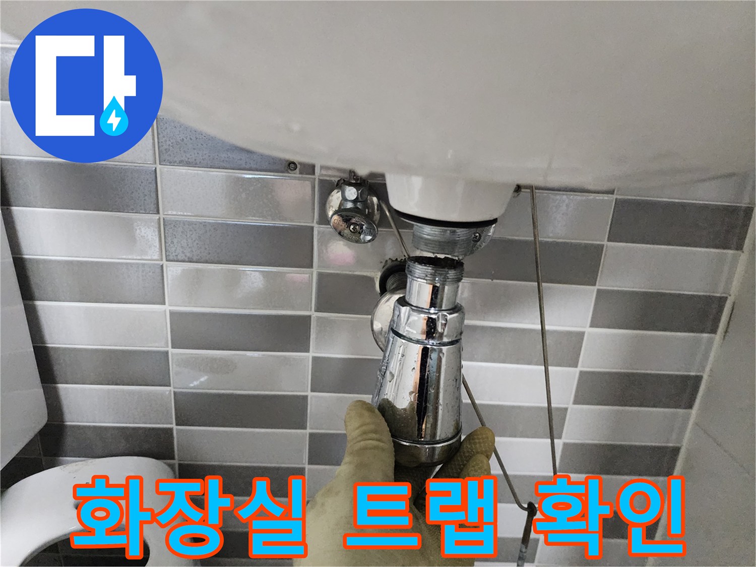 은색 크롬 배관과 세면대 하단 연결 부위를 엔지니어가 점검하고 있습니다.