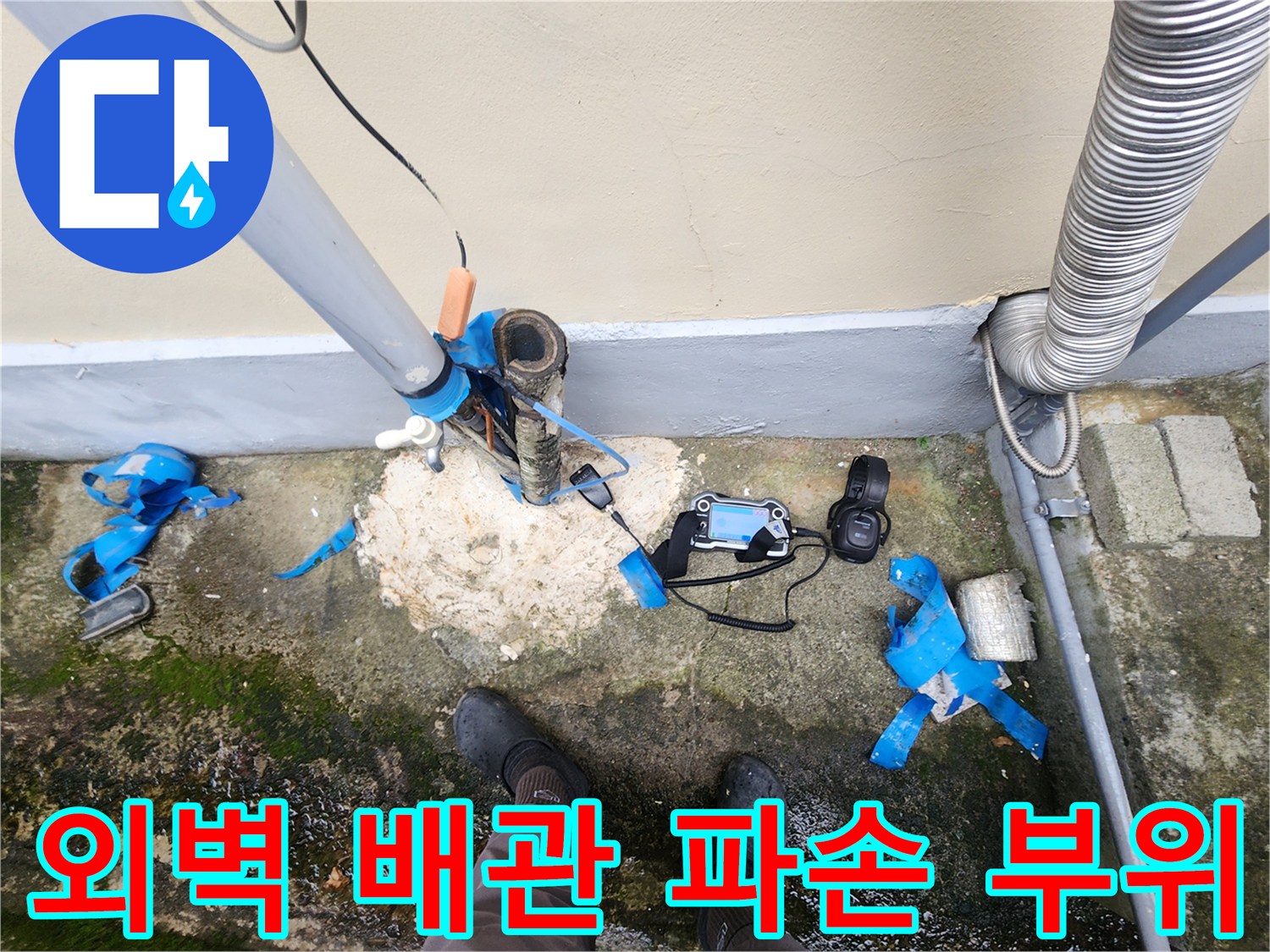 건물 외벽에 연결된 매립 배관의 파손 및 노출 상태를 보여주는 사진입니다.