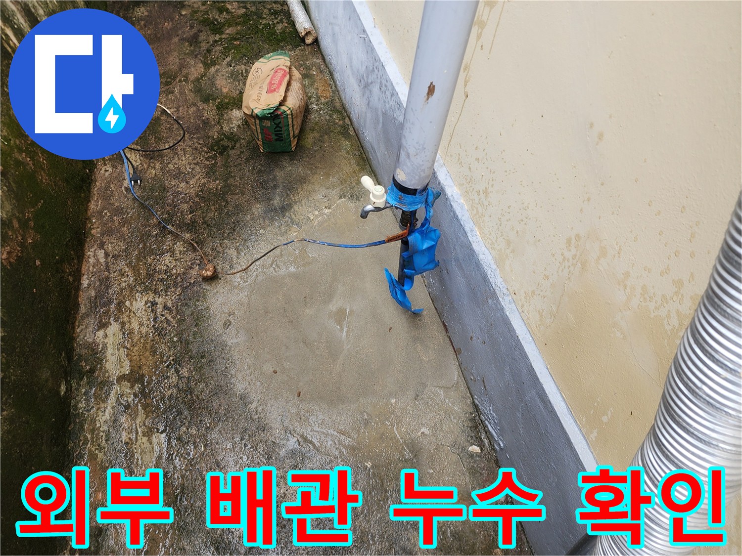 건물 외벽에 연결된 외부 배관의 파손 부위를 점검하는 모습입니다.