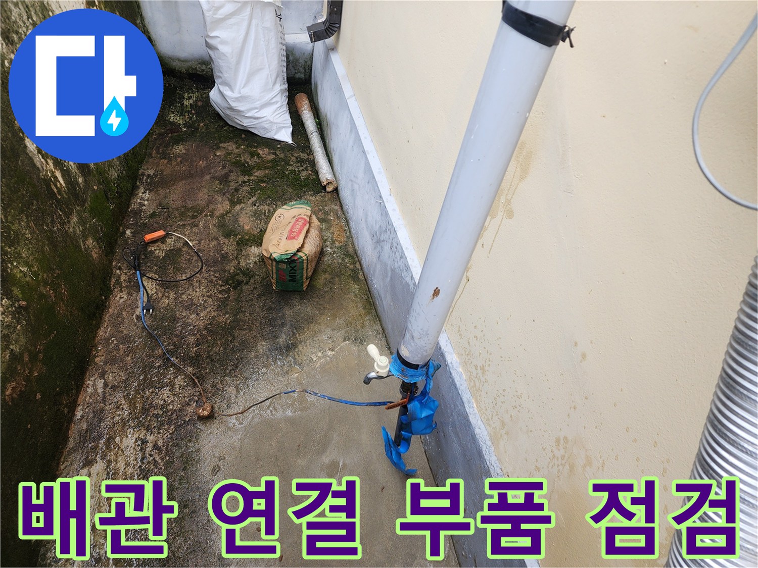 벽면에 붙은 수직 배관과 파란색 부속의 근접 촬영