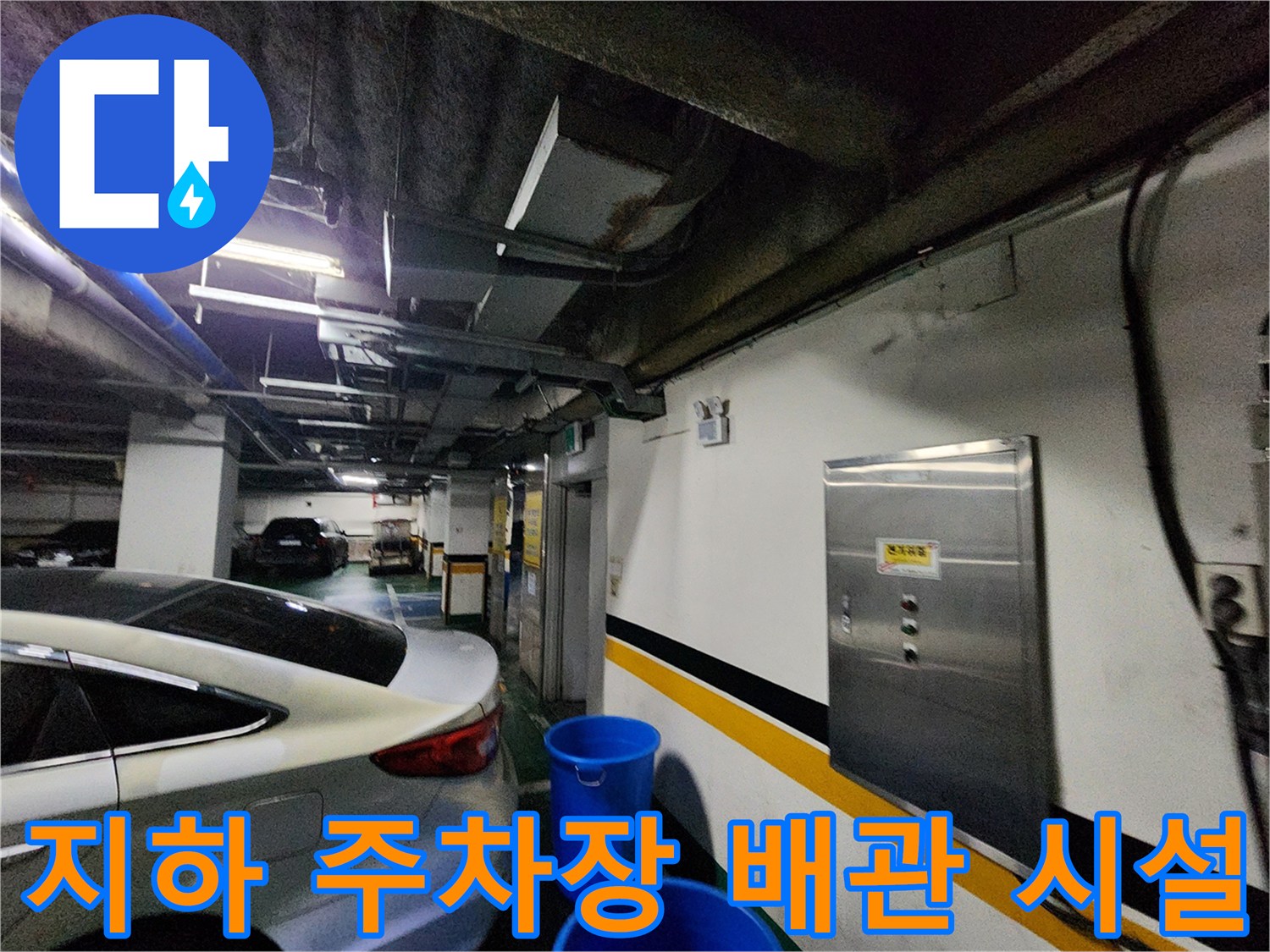 주차장 천장에 설치된 배관과 벽면 분전함 근처의 모습입니다.