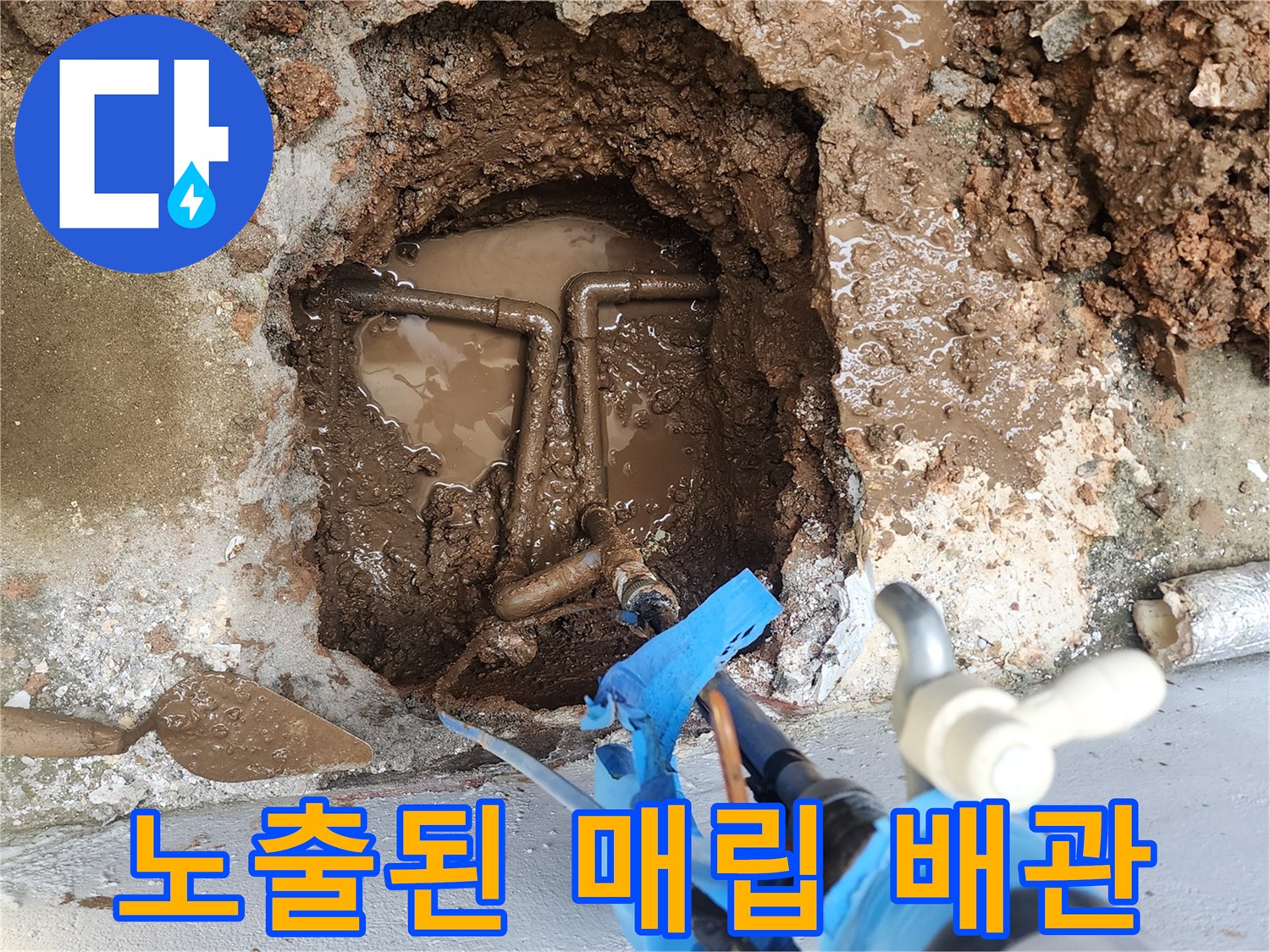 지면 아래 젖은 흙 속에 드러난 파손된 배관 연결 부위