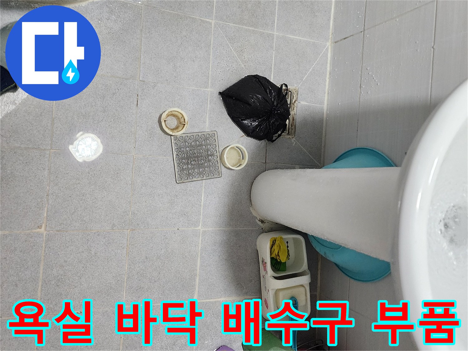 세면대 하부의 탈거된 배수구 부속과 타일 바닥 모습