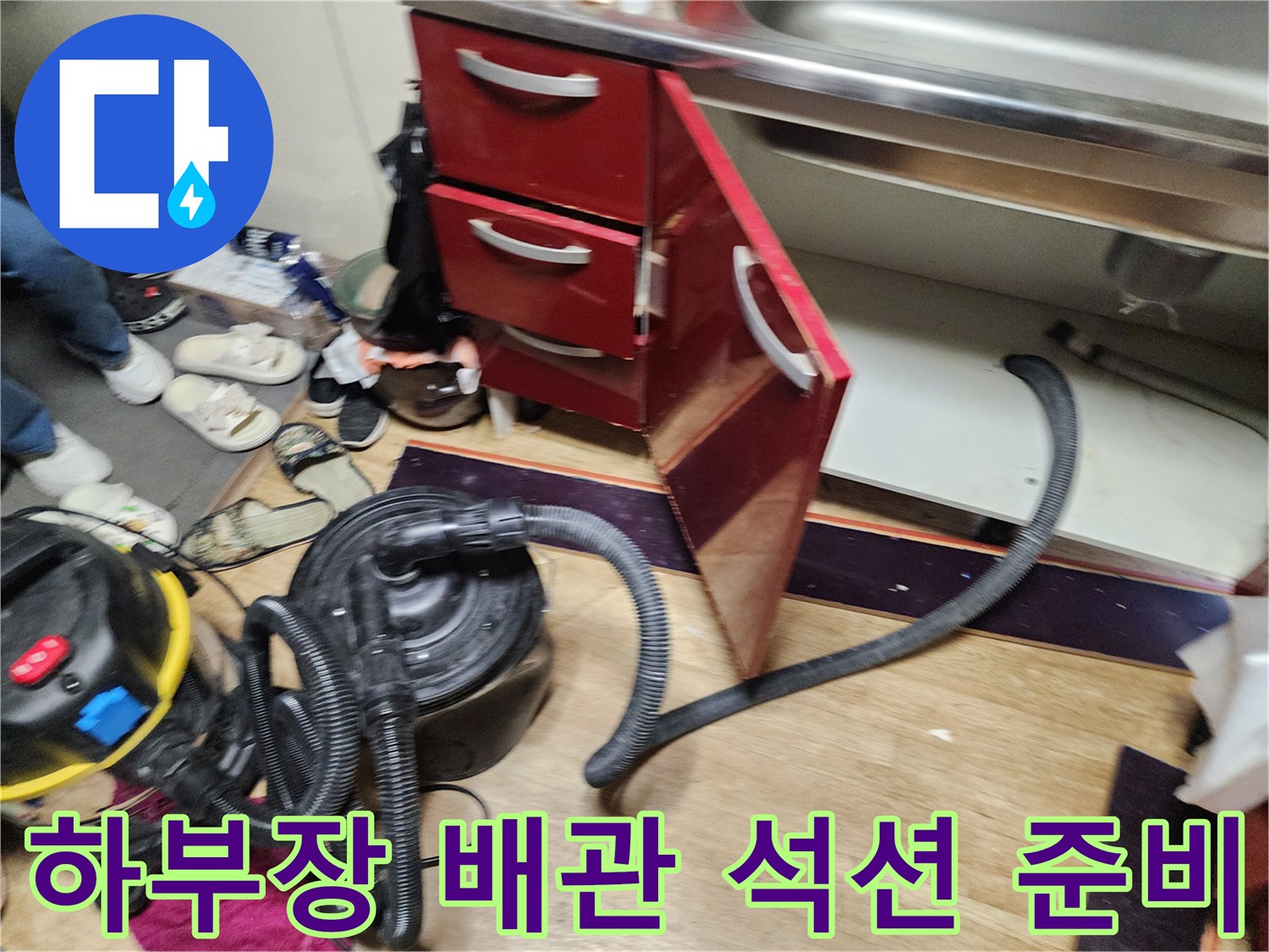 싱크대 하부장 아래쪽 배관 청소를 위해 배치된 석션 장비와 호스