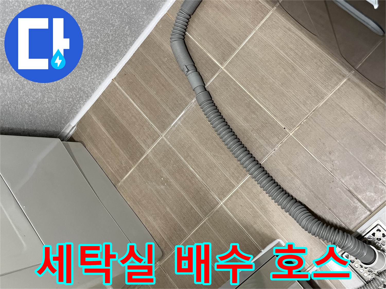 세탁기에서 연결된-회색 배수 호스와 바닥 타일의 모습