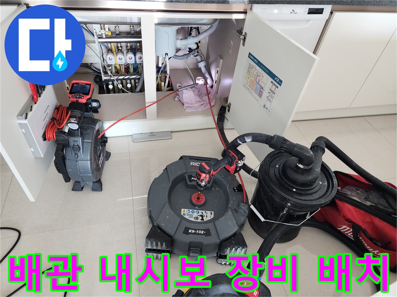 RIDGID 배관 내시경과 석션기가 싱크대 하부 배관 근처에 놓여 있는 장면