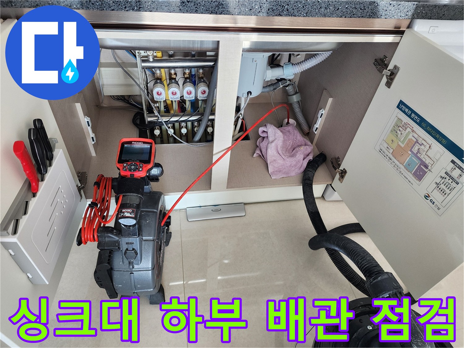 주방 싱크대 아래쪽 배관과 전문 탐지 장비가 놓여 있는 모습