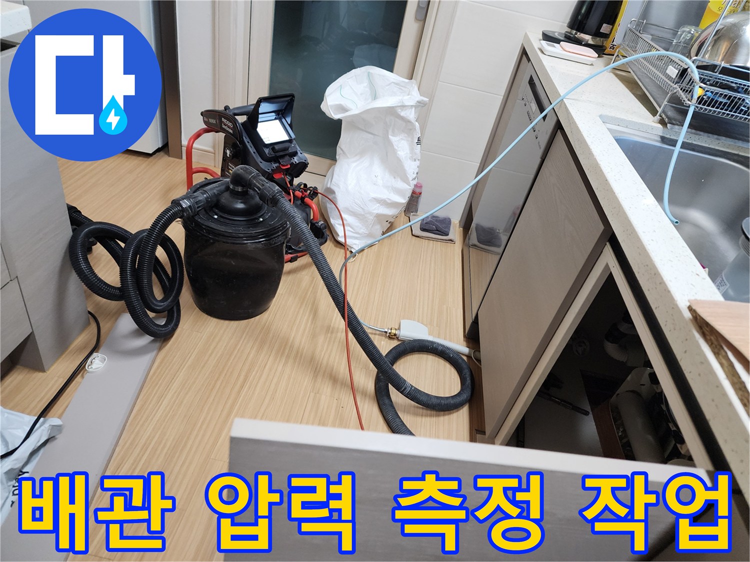 싱크대 아래 공간에 설치된 배관 공압 테스트용 장비와 호스 연결 상태